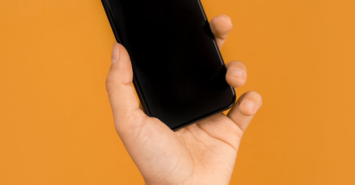 Close-up of a hand holding a smartphone against a bright orange backdrop, emphasizing modern technology.
